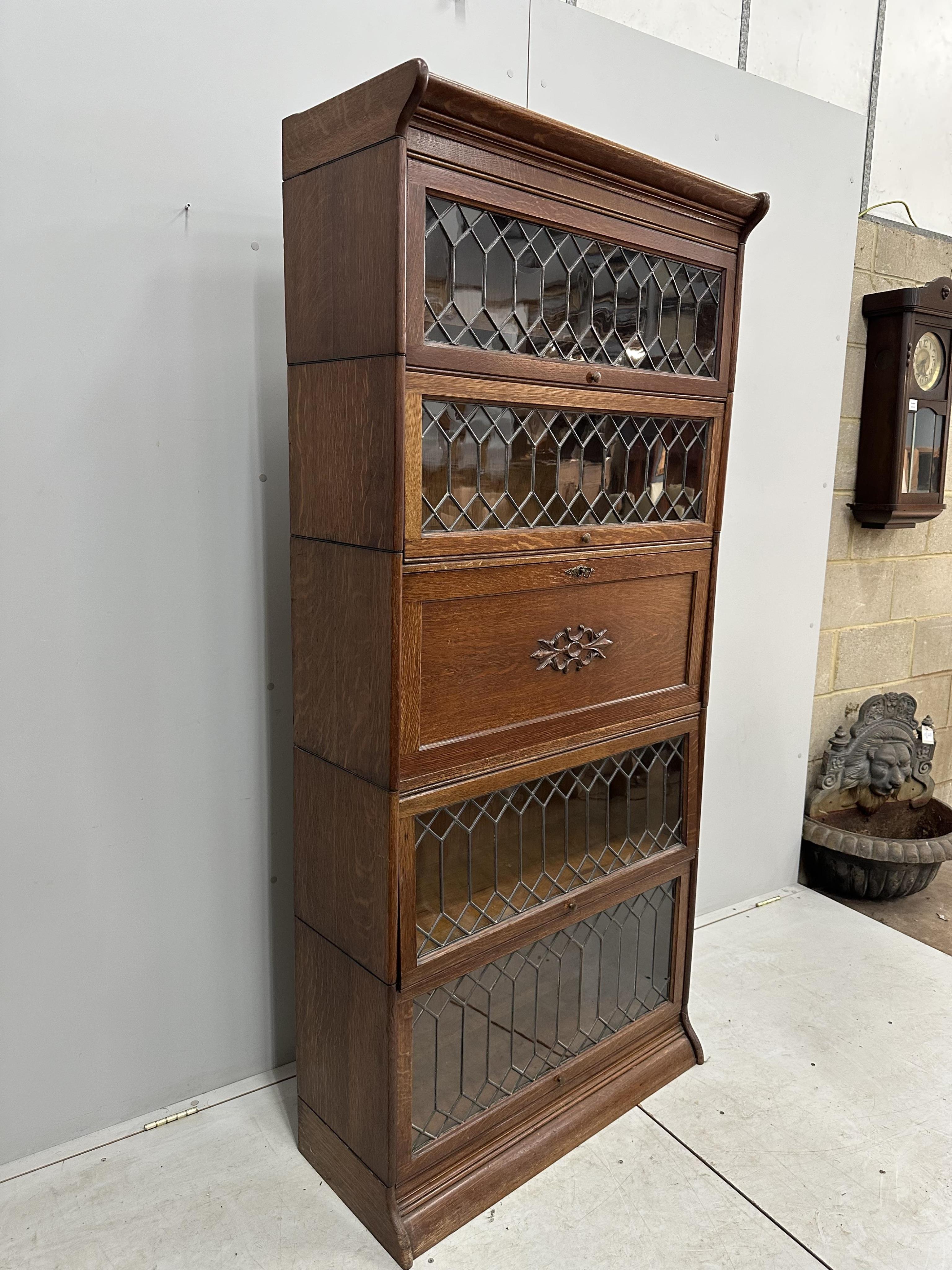 Attributed to Globe Wernicke, an oak five section bookcase incorporating secretaire compartment, width 87cm, height 190cm. Condition - good restored, back panels have been replaced